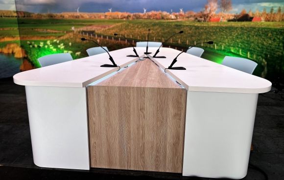 Moderne talkshowtafel met ingebouwde microfoons en houten afwerking in een corporate in-house studio, ontworpen door GetyourStudio