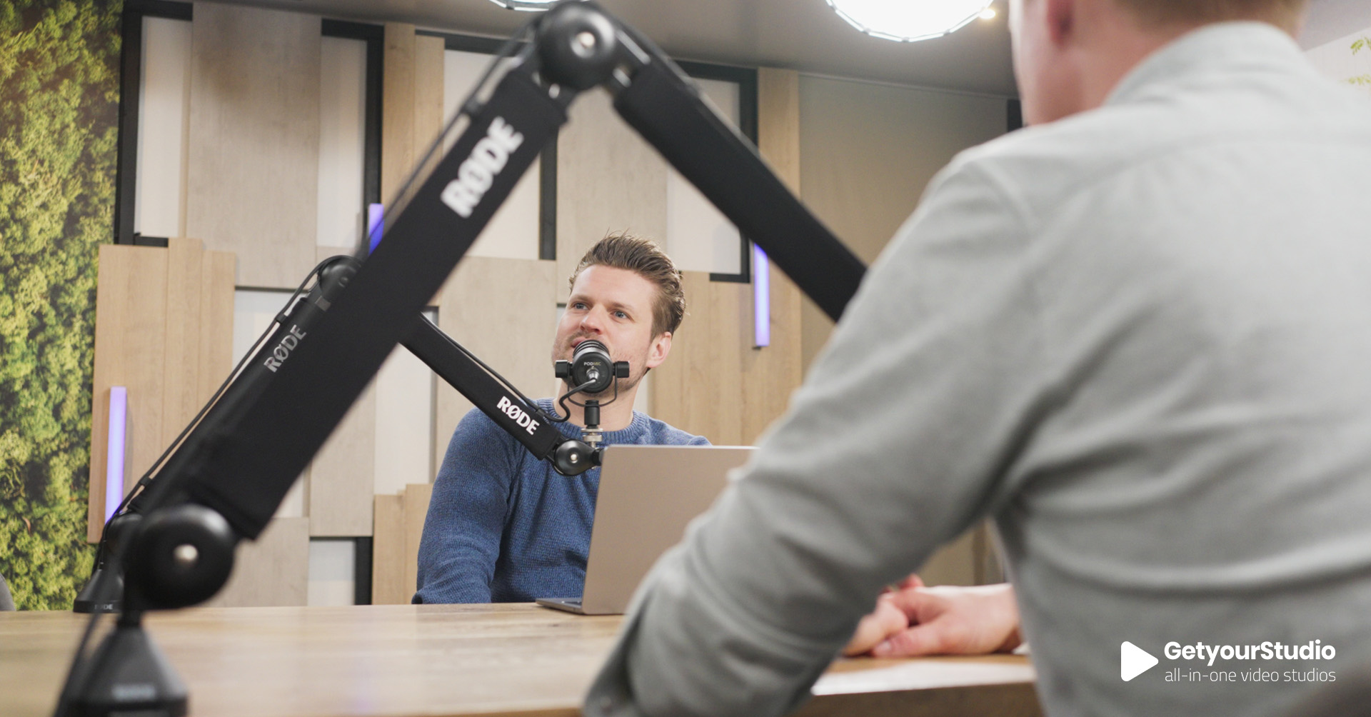 Podcastopname in een in-house corporate studio, ingericht door GetyourStudio met professionele microfoons en akoestisch decor.”