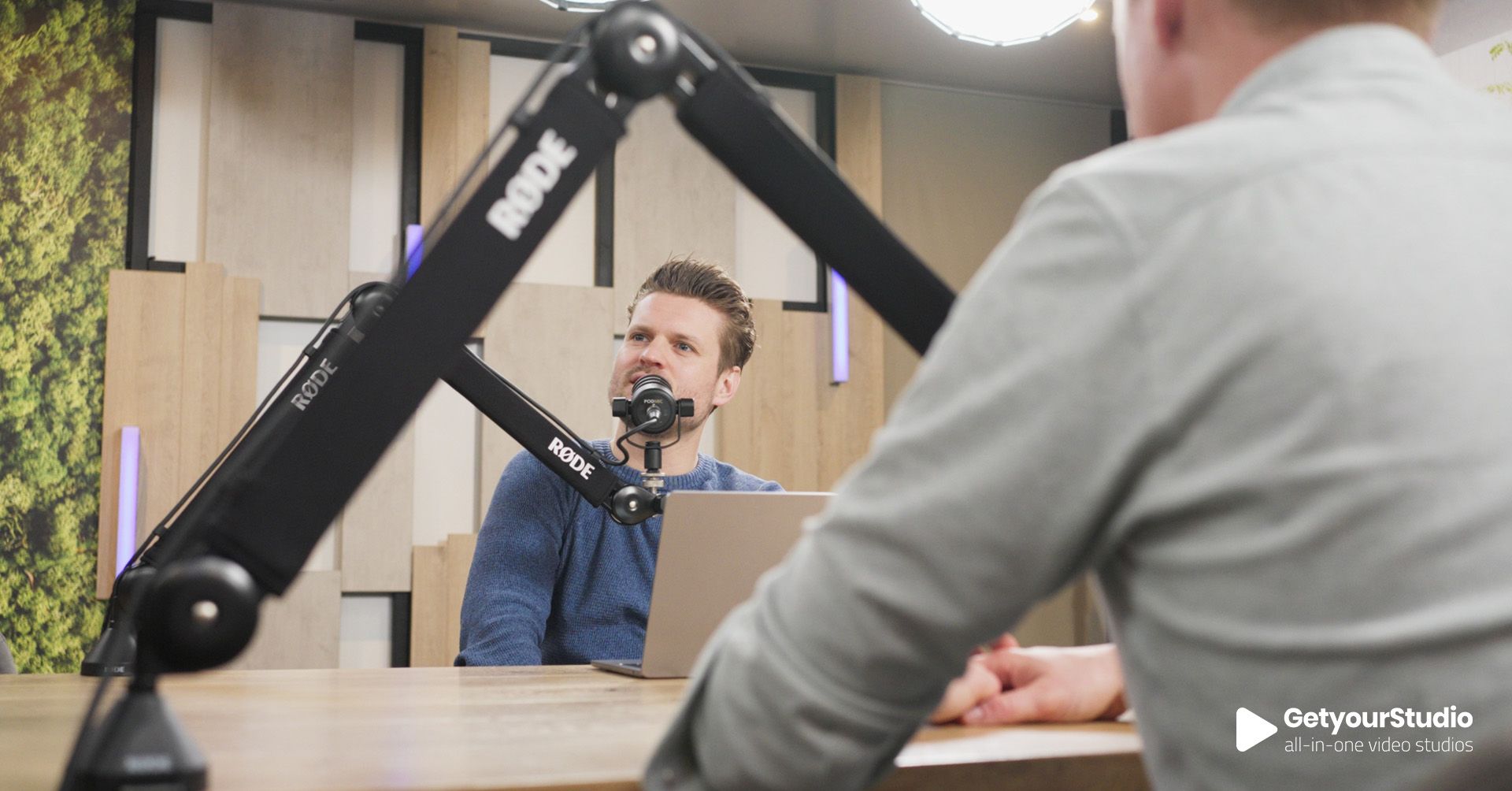Podcastopname in een in-house corporate studio, ingericht door GetyourStudio met professionele microfoons en akoestisch decor.”